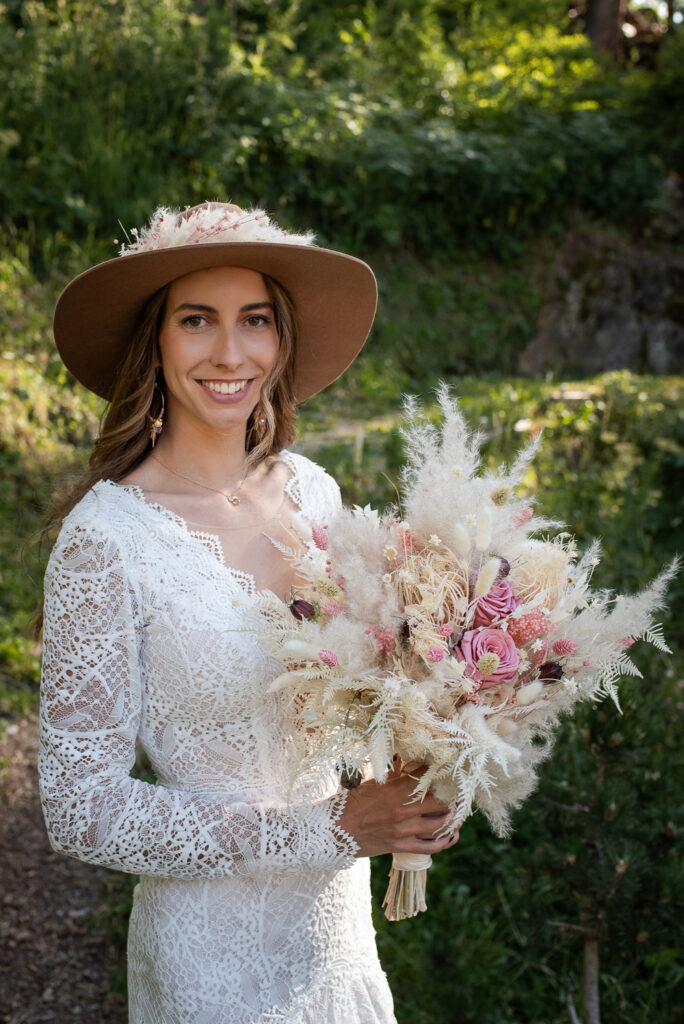Braut zeigt ihre herrlichen Trockenblumen bei dem Shooting im Wald.